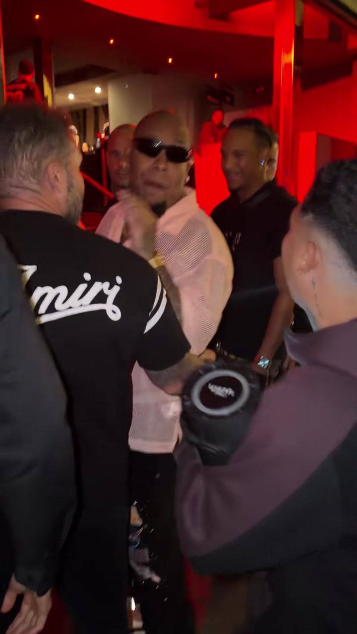 Pink-shirted performer behind a portable speaker at a red-lit entrance